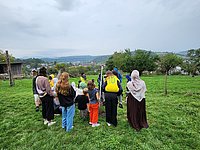Gruppe von Kindern und Betreuern auf einem Feld, mit dem Rücken zum Betrachter stehend